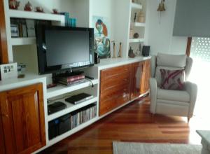 ein Wohnzimmer mit einem Flachbild-TV und einem Stuhl in der Unterkunft Silgar I in Sanxenxo