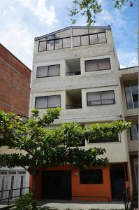 ein großes Apartmenthaus mit einem Baum davor in der Unterkunft Habita Estudios Laureles in Medellín