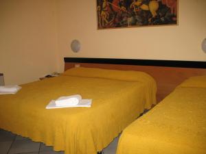 two beds in a room with yellow sheets and towels at Albergo Paradiso in Montecatini Terme