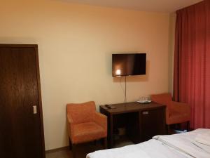 Habitación de hotel con cama, escritorio y TV. en Garni Hotel Cosmopolitan, en Senec