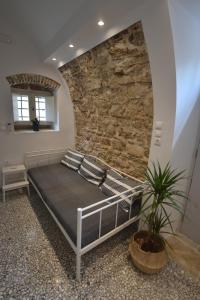 a bedroom with a bed in front of a stone wall at Yiasemi Corfu Luxury Studio in Corfu