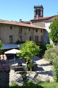 an old building with a tree and an umbrella at La Paresse en Douce in Tours-sur-Meymont