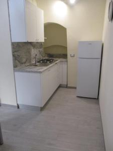 una cucina con armadietti bianchi e frigorifero bianco di Cavour17 a Montescaglioso