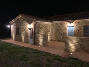 una casa de piedra por la noche con luces encendidas en Cordella In Valdorcia Truffle and Olive Oil Resort, en Montalcino