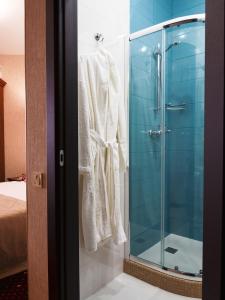 a bathroom with a glass shower with a robe at ArcadiaSky in Odesa
