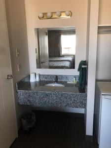 baño con lavabo y espejo grande en Arbour Ridge Inn & Suites, en Kindersley