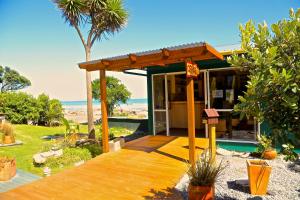 Punakaiki Beach Hostel في بوناكايكي: منزل على الشاطئ مع شرفة خشبية