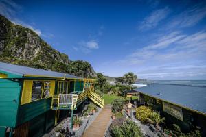 a house on the side of a hill next to the ocean at Punakaiki Beach Hostel in Punakaiki