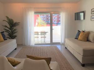 a living room with two white couches and a sliding glass door at Alto Mar Apartment in Peniche