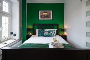 グダニスクにあるGedanum Apartmentの緑のベッドルーム(タオル付きのベッド付)