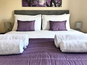 um quarto com uma cama grande com lençóis e almofadas roxos em Liberty Locking Castle em Weston-super-Mare