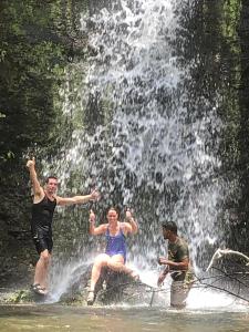 three people standing in front of a waterfall at Balbo's in Liberia