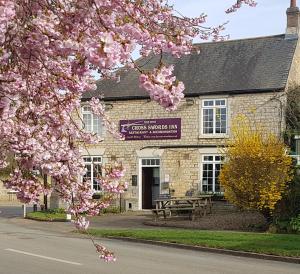 einen Baum mit rosa Blumen vor einem Gebäude in der Unterkunft Cross Swords Rooms, Skillington in Skillington
