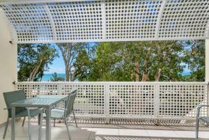 a table and chairs on a patio with a white fence at Hibiscus in Marlin Waters Palm Cove in Palm Cove