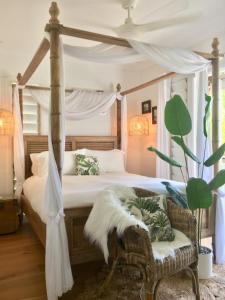 a bedroom with a canopy bed and a chair at Pandanus Cottage in Port Douglas