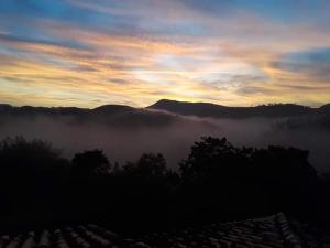 a view of a foggy valley at sunset with mountains at Pousada Cantinho de Deus in Conservatória