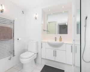 a white bathroom with a toilet and a sink at Apartment with Private PATIO, and PARK across the road in London