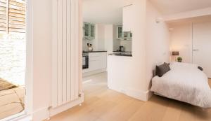 a white bedroom with a bed and a kitchen at Apartment with Private PATIO, and PARK across the road in London +4 photos