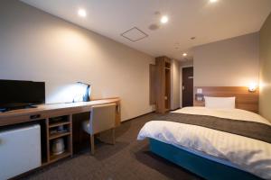 een hotelkamer met een bed en een bureau met een televisie bij HOTEL CITY INN WAKAYAMA Wakayama-Ekimae in Wakayama