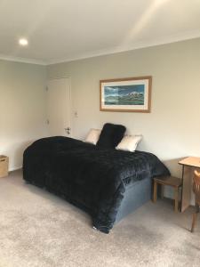 a bedroom with a bed with a black blanket at Broadfield in Rolleston