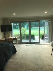 1 dormitorio con vistas al campo de golf a través de puertas correderas de cristal en Broadfield, en Rolleston