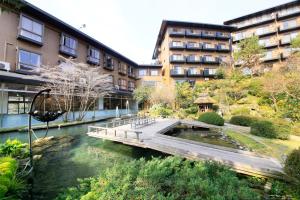 a bridge over a river in front of a building at Hotel Kamogawaso in Takekara