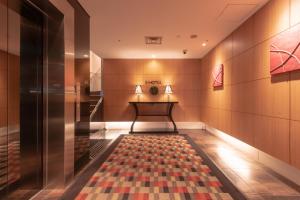 un pasillo con un banco y una alfombra en el suelo en E Hotel Higashi Shinjuku, en Tokio