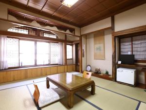 a living room with a coffee table and windows at Ikariya Ryokan in Yamanouchi +37 photos