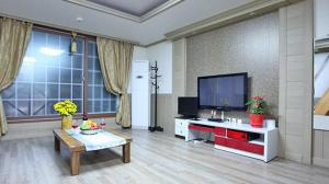 a living room with a flat screen tv and a table at Tongyeong Bada Sarang Pension in Tongyeong