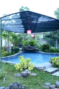 a large swimming pool with a canopy over it at RedDoorz Syariah Plus near Banyuwangi Airport in Dadapan