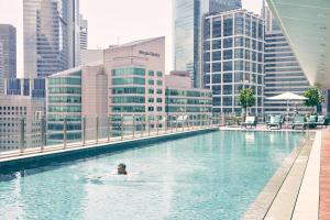 a person swimming in a pool in a city at Capri by Fraser China Square, Singapore in Singapore
