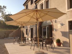 - une table et des chaises sous un parasol sur la terrasse dans l'établissement Bed & Breakfast Le Coste, à Lazise