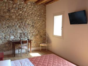 una camera da letto con tavolo e TV a parete di Bed & Breakfast Le Coste a Lazise