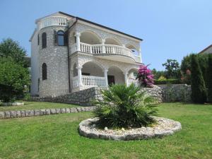 a large stone house with a balcony on a yard at Apartments Villa Sandra in Opatija