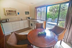 a kitchen with a wooden table and chairs and a table at The Shingles Riverside Cottages in New Norfolk