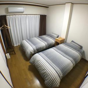 two beds in a small room with a window at machiyado Kuwanajuku Kawaguchi-cho 8 in Kuwana