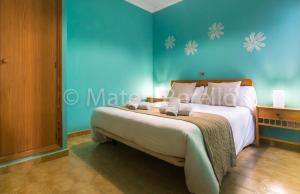 a bedroom with a large bed with a blue wall at Orellana in Can Picafort