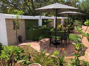 a patio with a table and chairs and an umbrella at Summer Garden Guest House (Urban Jungle) in Benoni