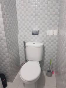 ein Badezimmer mit einer weißen Toilette in einer gefliesten Wand in der Unterkunft KVA Syariah 4BR in Bekasi