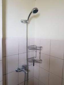 eine Dusche mit drei Ablagen an einer weiß gefliesten Wand in der Unterkunft KVA Syariah 4BR in Bekasi + 29 Fotos