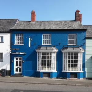 a blue house with white windows on a street at The Blue Mantle in Wellington