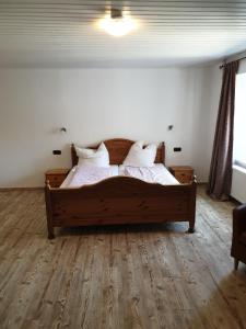 Schlafzimmer mit einem Holzbett mit weißer Bettwäsche und Kissen in der Unterkunft Gastehaus in der Alte Kellerei in Kobern-Gondorf
