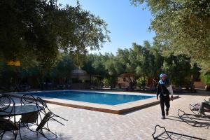 una mujer caminando por una piscina en Haven La Chance Desert Hotel, en Merzouga