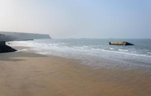 an empty beach with a pier in the water at Fenêtres sur Mer Arromanches in Arromanches-les-Bains