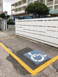 a handicapped sign on the ground next to a white fence at Hotel Atlantic in Senigallia