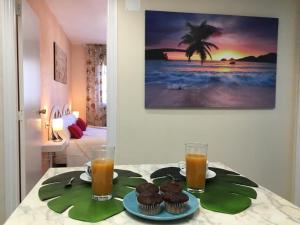 a table with cupcakes and two glasses of orange juice at Apartamento AGUA MARINA Levante Beach in Benidorm