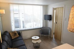 een woonkamer met een bank, een stoel en een raam bij Bleyendaal aan Zee in Egmond aan Zee