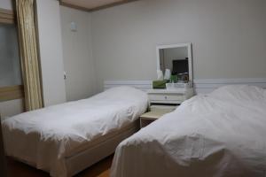 duas camas num quarto de hotel com um espelho e uma cama sidx sidx sidx em Orasung Motel em Jeju