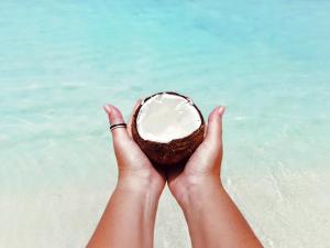 a person holding a coconut in front of the ocean at Havana Hideaway in Gili Trawangan