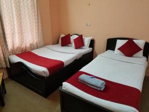 2 camas en una habitación de hotel con almohadas rojas y blancas en HOTEL ICE VIEW POKHARA, en Pokhara
